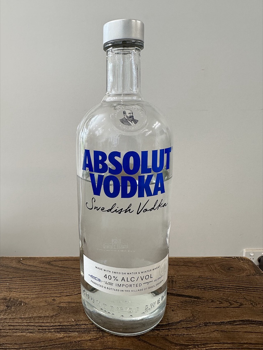 A bottle of Absolut Vodka standing on a wood table (used as a stand-in for the ad-collecting hobby, since the Absolut ads themselves are copyrighted)