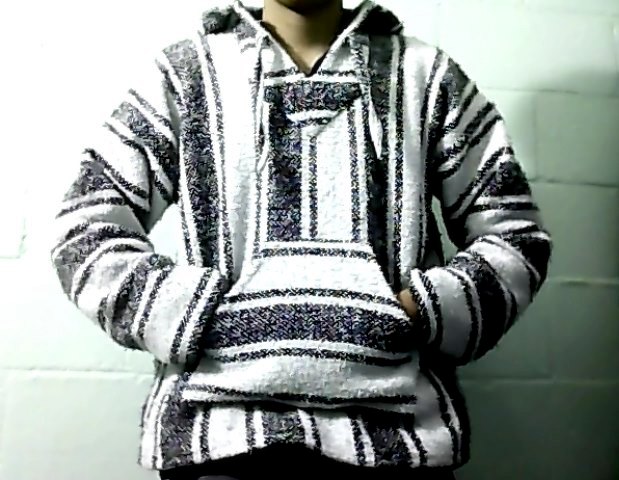 A person wearing a black-and-white striped Baja hoodie with hands in the front pouch pocket