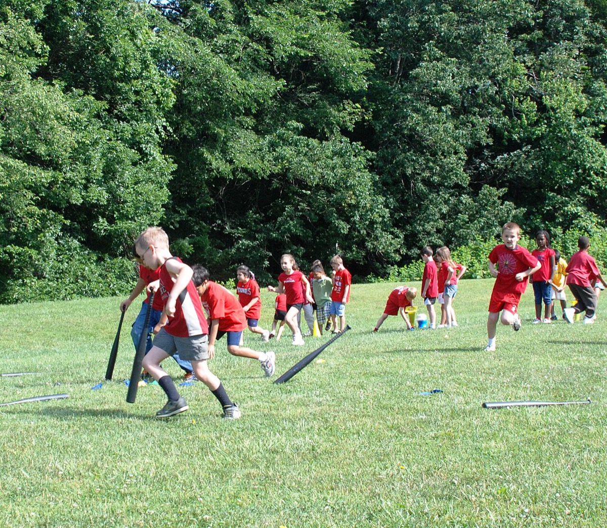 Elementary-school kids in matching shirts playing outdoor games on a grassy field at a school field day