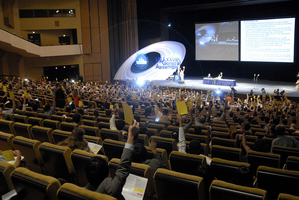 Astronomers raise yellow cards to vote on the planet definition at the 2006 IAU General Assembly in Prague — the vote that demoted Pluto