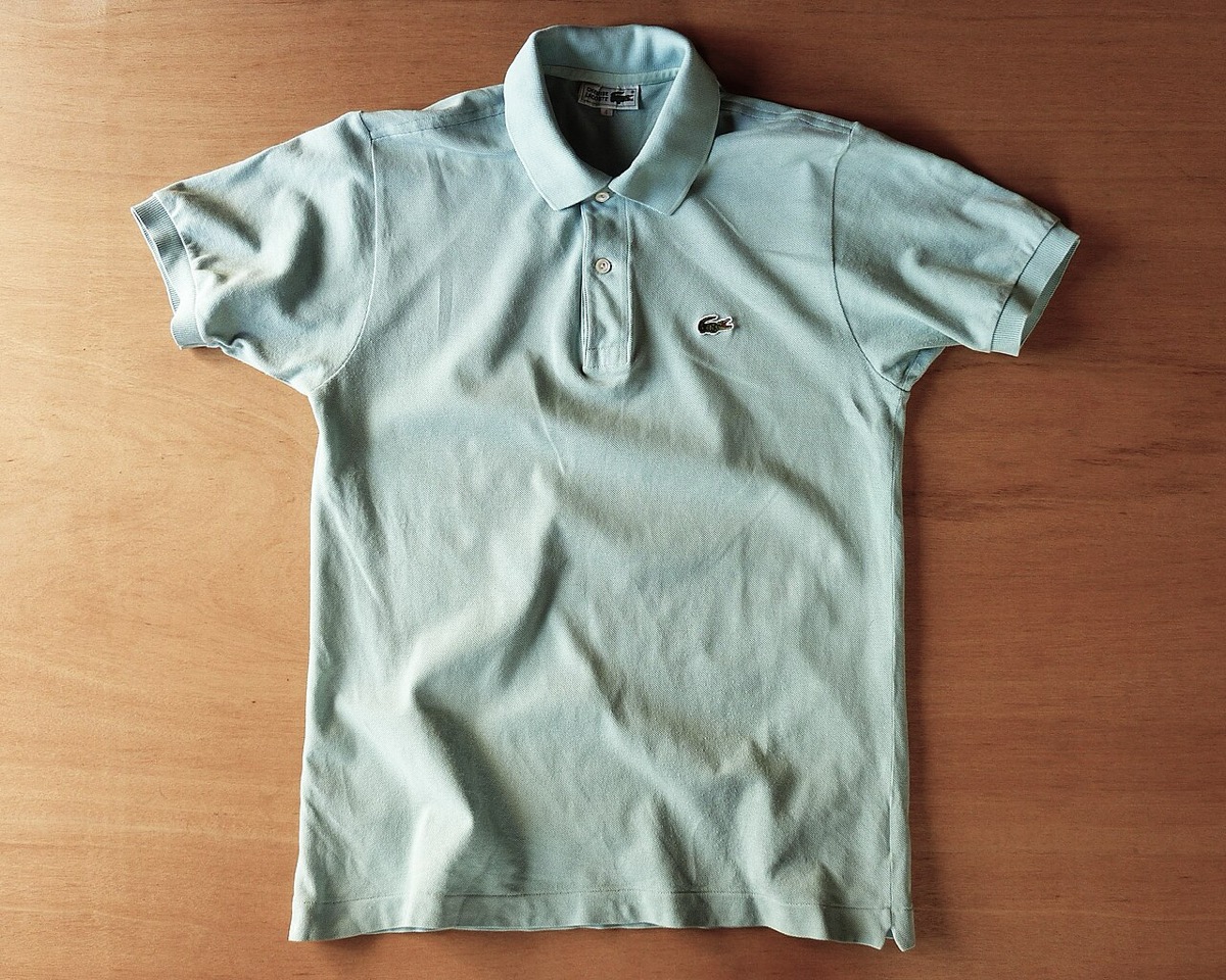 A vintage 1990s Lacoste piqué polo shirt laid flat — the kind of collar the 2000s trend flipped up