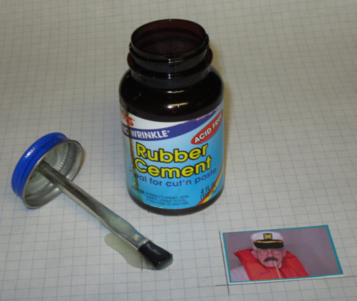 An open jar of rubber cement with its brush-in-the-cap applicator