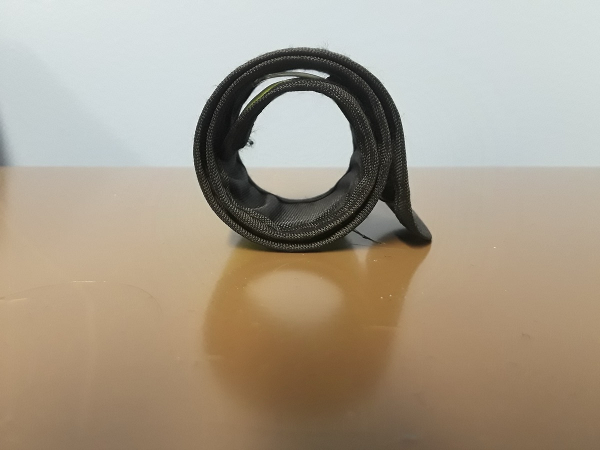 A slap bracelet coiled into its snapped-closed spiral, photographed from the side