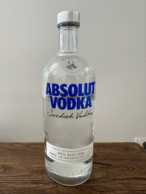 A bottle of Absolut Vodka standing on a wood table (used as a stand-in for the ad-collecting hobby, since the Absolut ads themselves are copyrighted)