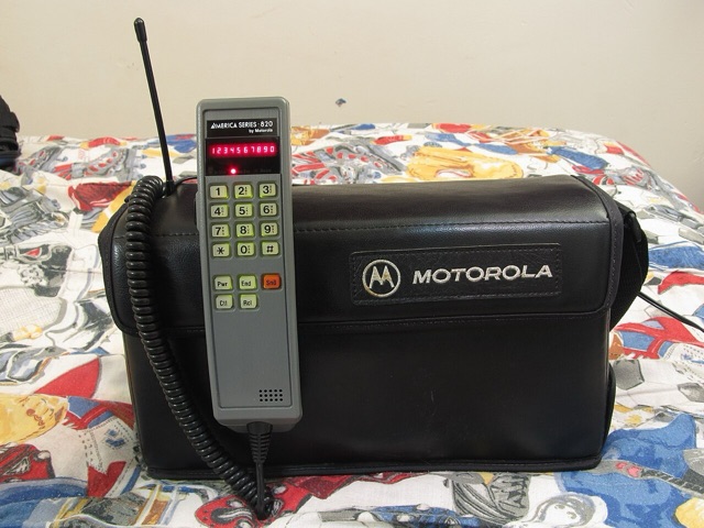A Motorola America Series 820 bag phone with its gray handset resting on the black leather bag