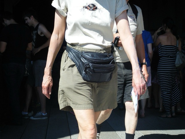 A black leather fanny pack worn at the waist over khaki shorts in a crowd, 2011