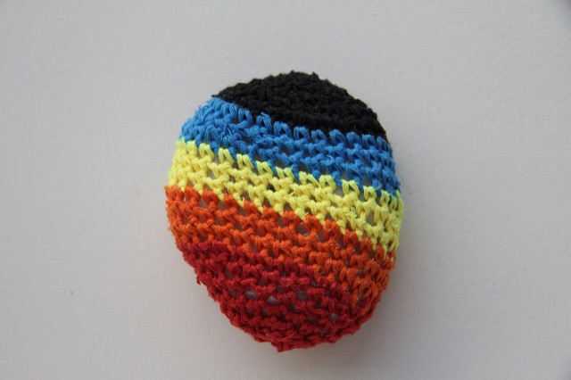 A multicolored crocheted hacky sack on a white background