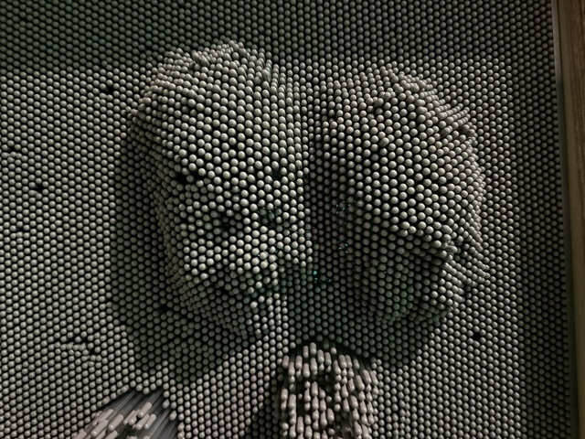 A pin-art pinscreen board holding the 3D impressions of two faces pressed into its pins