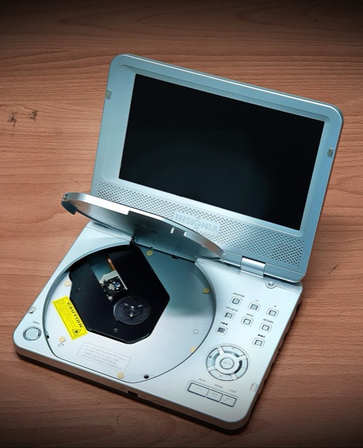 A silver Insignia portable DVD player, open with the screen up and the disc tray exposed
