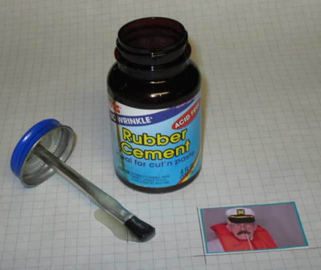An open jar of rubber cement with its brush-in-the-cap applicator
