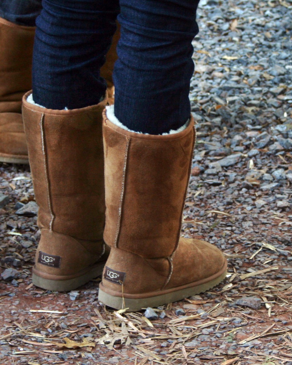 A pair of chestnut UGG boots worn with jeans tucked in, close-up on the boots