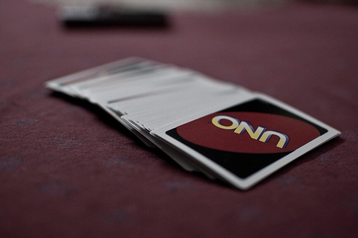 A spread Uno deck on a table, the red-oval UNO card back facing up