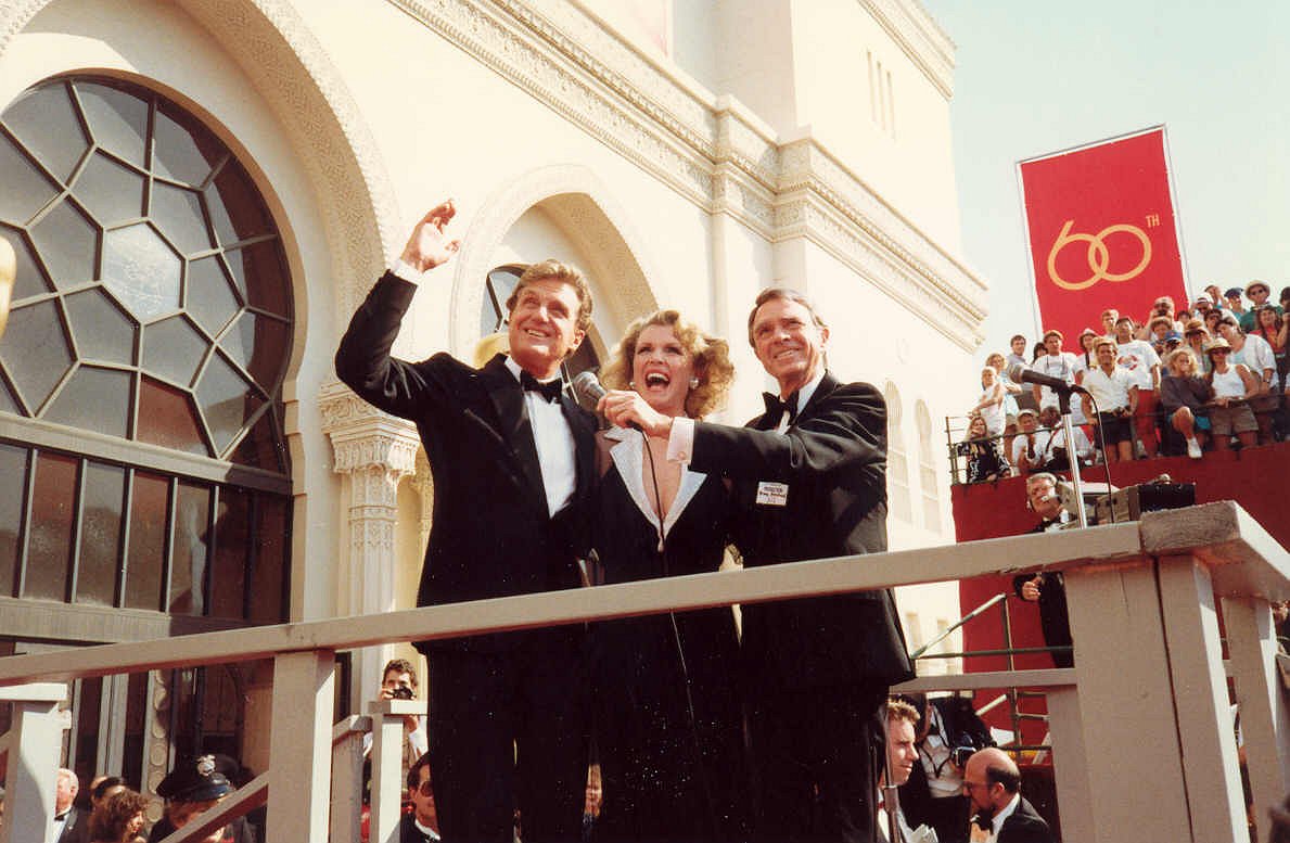 Host Robert Stack, waving at left, on the red carpet at the 1988 Academy Awards